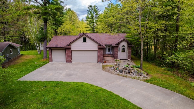 41 W River Dr, Gladwin, MI 48624 - view of front facade with brick siding, a front yard, driveway, a wooded view, and an attached garage