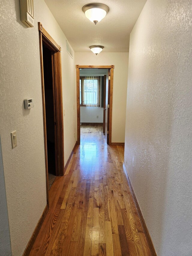 41 W River Dr, Gladwin, MI 48624 - hallway with light wood-type flooring, a textured wall, and baseboards