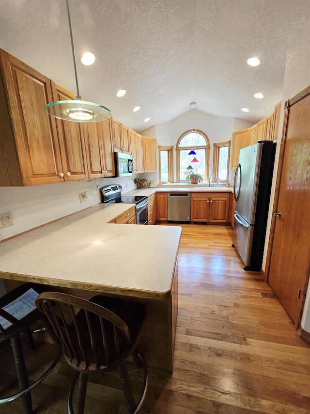41 W River Dr, Gladwin, MI 48624 - kitchen with stainless steel appliances, lofted ceiling, a textured ceiling, light wood-type flooring, and a peninsula