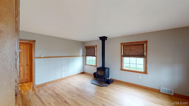 730 Elliott Ave, Ishpeming, MI 49855 - empty room with a wood stove, wood finished floors, healthy amount of natural light, and baseboards