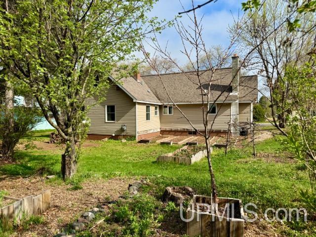 730 Elliott Ave, Ishpeming, MI 49855 - rear view of house featuring a chimney, a yard, and a vegetable garden