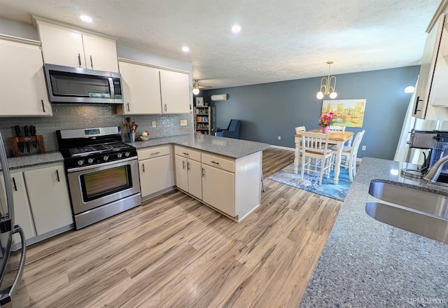 14 Arrowhead Dr, Marquette, MI 49855 - kitchen with appliances with stainless steel finishes, a sink, a peninsula, light wood finished floors, and white cabinetry