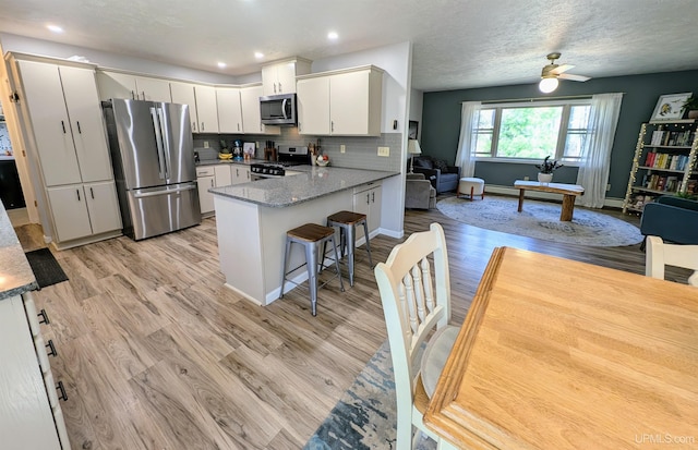 14 Arrowhead Dr, Marquette, MI 49855 - kitchen with stainless steel appliances, open floor plan, a peninsula, a ceiling fan, and light wood-type flooring