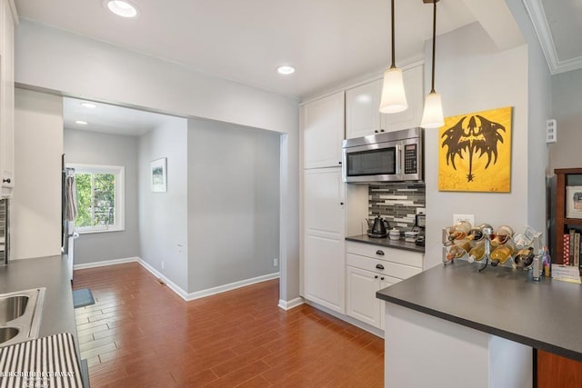 1131 Boyd St, Troy, MI 48083 - kitchen featuring stainless steel microwave, dark countertops, decorative backsplash, baseboards, and white cabinets