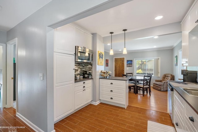 1131 Boyd St, Troy, MI 48083 - kitchen with appliances with stainless steel finishes, wood finished floors, decorative backsplash, dark countertops, and ornamental molding