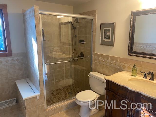 18918 Canal Rd, Houghton, MI 49931 - full bathroom featuring tile walls, toilet, a shower stall, wainscoting, and tile patterned floors