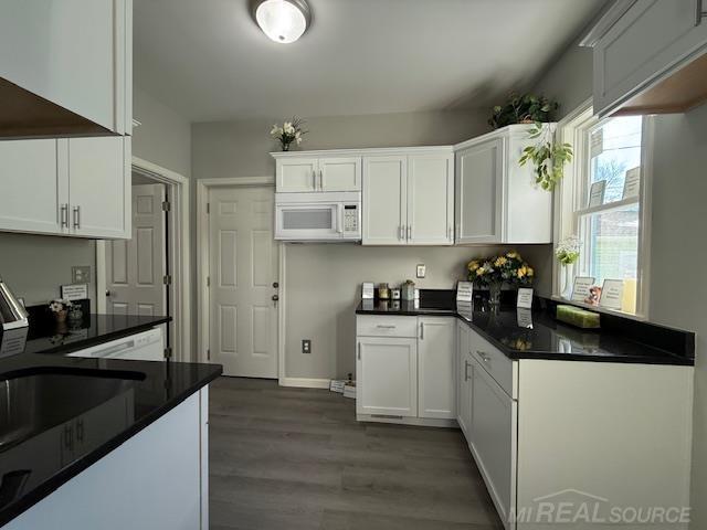 1416 Kearney St, Port Huron, MI 48060 - kitchen featuring white microwave, dark wood finished floors, white cabinets, dark countertops, and baseboards