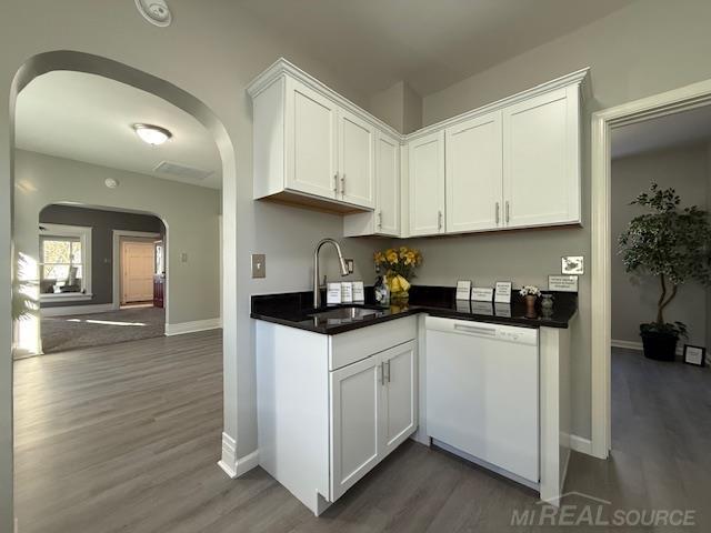 1416 Kearney St, Port Huron, MI 48060 - kitchen featuring white dishwasher, arched walkways, a sink, wood finished floors, and white cabinets