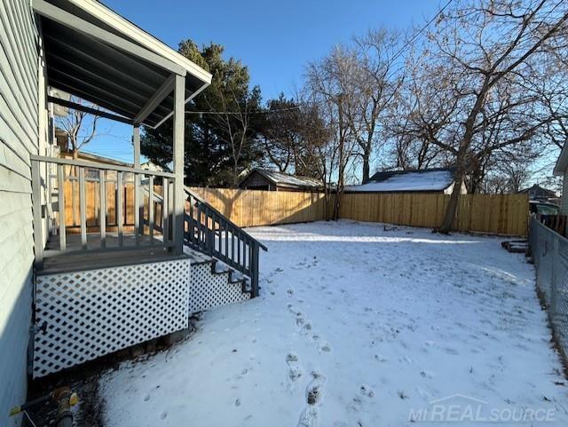 1416 Kearney St, Port Huron, MI 48060 - snowy yard featuring a fenced backyard and a wooden deck