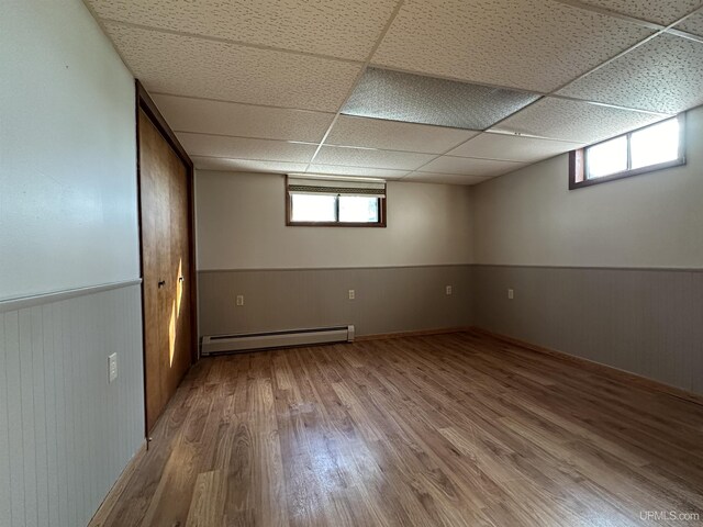 9014 Stagecoach Q.5 Ave, Gladstone, MI 49837 - below grade area with a baseboard radiator, wood finished floors, a drop ceiling, a wainscoted wall, and wood walls