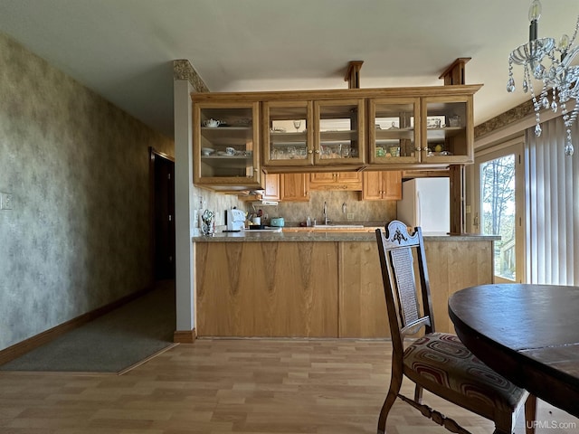 9014 Stagecoach Q.5 Ave, Gladstone, MI 49837 - kitchen featuring freestanding refrigerator, light wood-style floors, glass insert cabinets, a sink, and tasteful backsplash