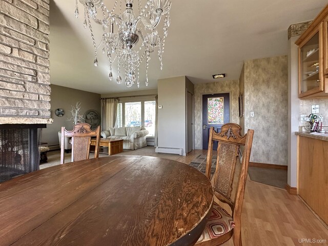 9014 Stagecoach Q.5 Ave, Gladstone, MI 49837 - dining room featuring baseboard heating, a chandelier, light wood-style flooring, a multi sided fireplace, and baseboards
