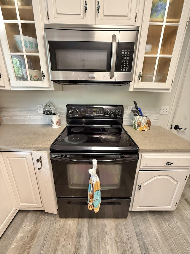 555 W Saxton Rd, Sanford, MI 48657 - kitchen featuring black range with electric cooktop, stainless steel microwave, light countertops, and light wood finished floors