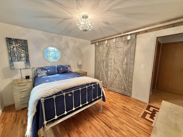 555 W Saxton Rd, Sanford, MI 48657 - bedroom featuring wood finished floors, a chandelier, a barn door, and baseboards