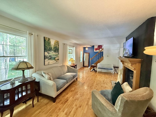 555 W Saxton Rd, Sanford, MI 48657 - living room featuring stairs, a textured ceiling, light wood finished floors, and a glass covered fireplace