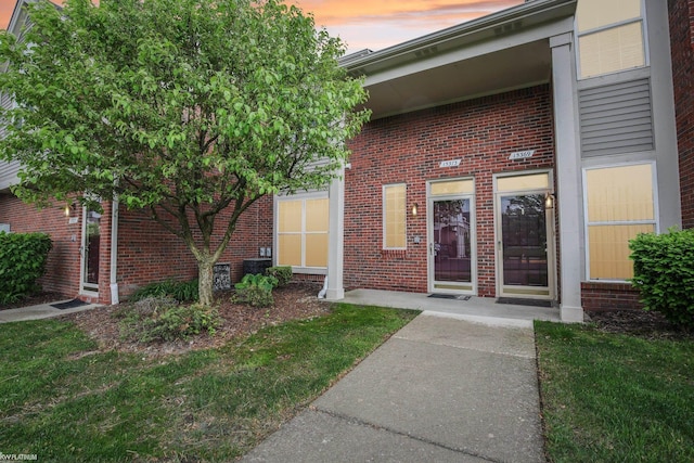 exterior entry at dusk featuring brick siding