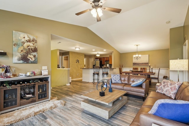 living area with vaulted ceiling, a ceiling fan, a chandelier, wood finished floors, and baseboards