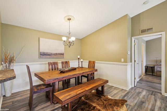 dining area with wood finished floors, a chandelier, baseboards, and vaulted ceiling