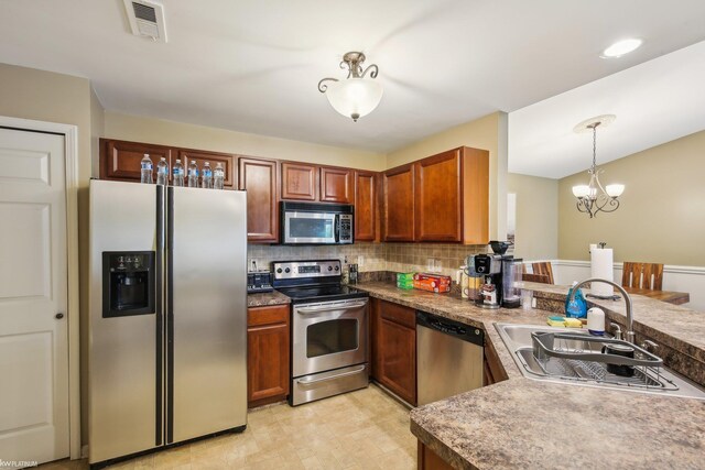kitchen with stainless steel appliances, a sink, decorative backsplash, a chandelier, and brown cabinetry