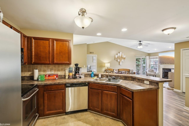 kitchen featuring appliances with stainless steel finishes, a sink, a peninsula, dark countertops, and ceiling fan