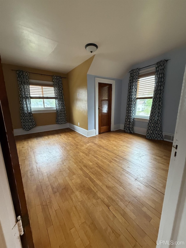 404 W Ludington St, Iron Mountain, MI 49801 - empty room with light wood finished floors, baseboards, and vaulted ceiling