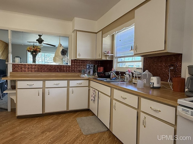 99 N Mitchell St, Gwinn, MI 49841 - kitchen with ceiling fan, light wood-type flooring, backsplash, white cabinets, and a sink