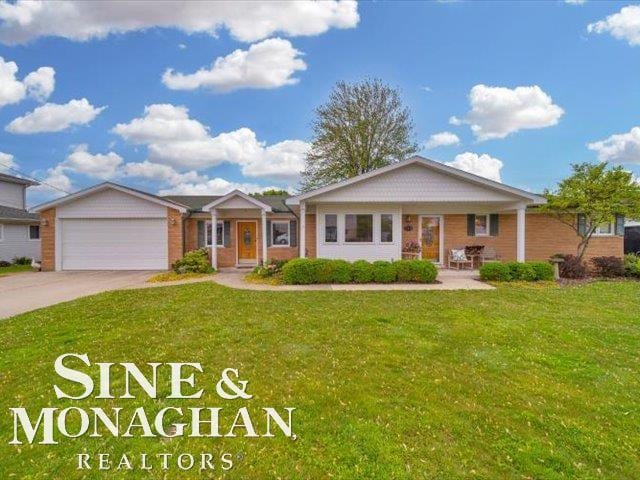 view of front of property with driveway, a front lawn, a garage, and brick siding