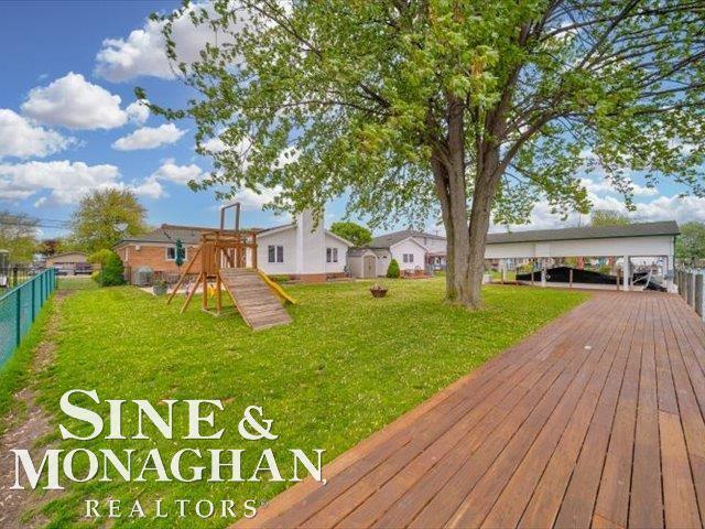 wooden deck with a playground and a carport