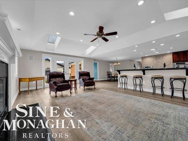 living room featuring wood finished floors, baseboards, recessed lighting, and a skylight