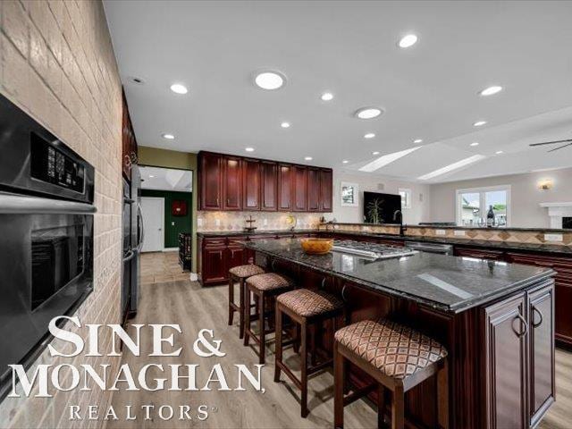 kitchen with a breakfast bar area, light wood-type flooring, a fireplace, backsplash, and recessed lighting