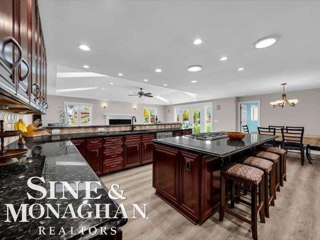 kitchen featuring dark brown cabinets, light wood-style floors, a sink, recessed lighting, and a chandelier