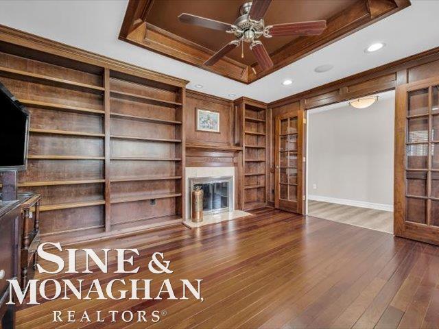 unfurnished living room with a glass covered fireplace, ceiling fan, wood finished floors, built in shelves, and recessed lighting