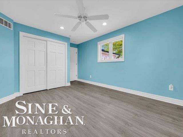 unfurnished bedroom featuring wood finished floors, baseboards, a closet, recessed lighting, and ceiling fan