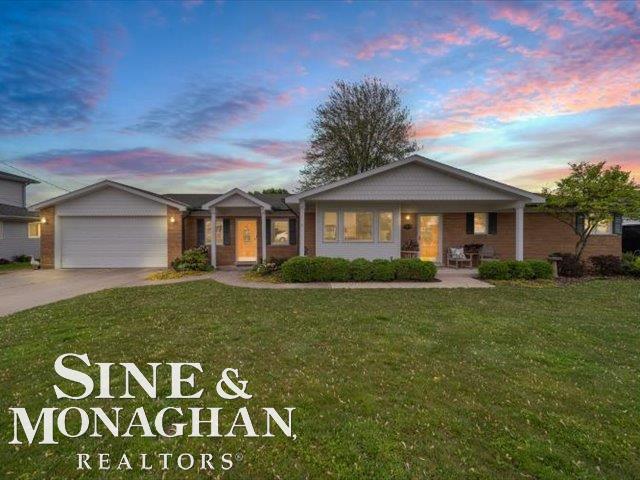 single story home featuring a lawn, driveway, a garage, and covered porch