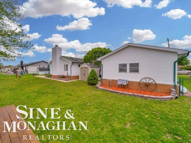 back of house with a storage unit, a yard, and an outdoor structure