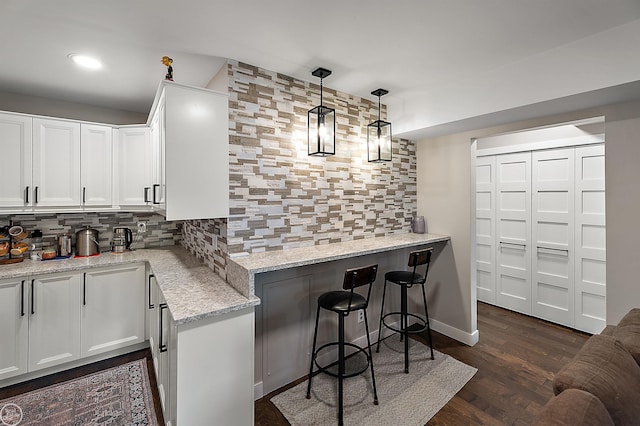2102 Pauline Blvd Unit 304, Ann Arbor, MI 48103 - kitchen featuring backsplash, light stone counters, white cabinetry, a breakfast bar area, and dark wood-type flooring