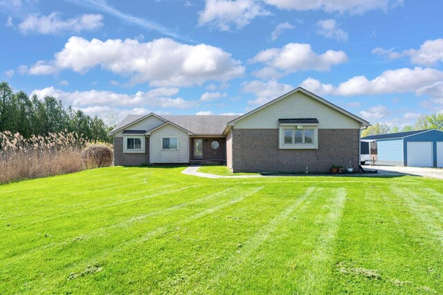 single story home with an outbuilding, a garage, a front lawn, and brick siding