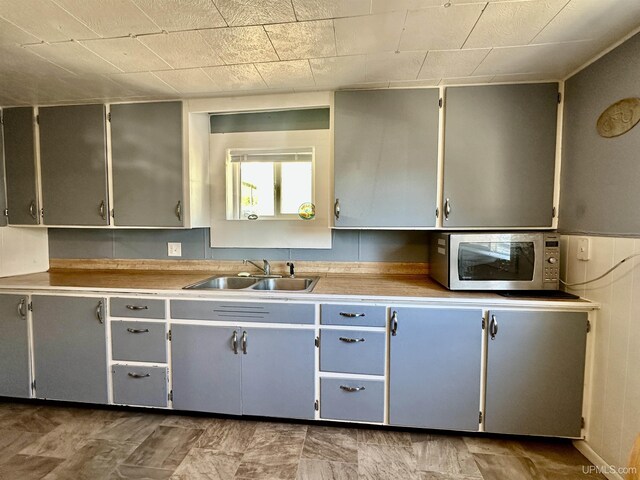 518 Lynn St, Munising, MI 49862 - kitchen with stainless steel microwave, a sink, gray cabinetry, and light countertops