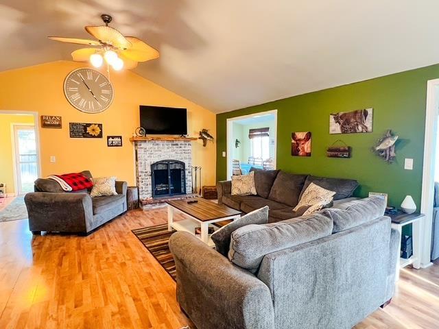 601 N Scott Dr, Farwell, MI 48622 - living area with vaulted ceiling, wood finished floors, ceiling fan, a brick fireplace, and plenty of natural light