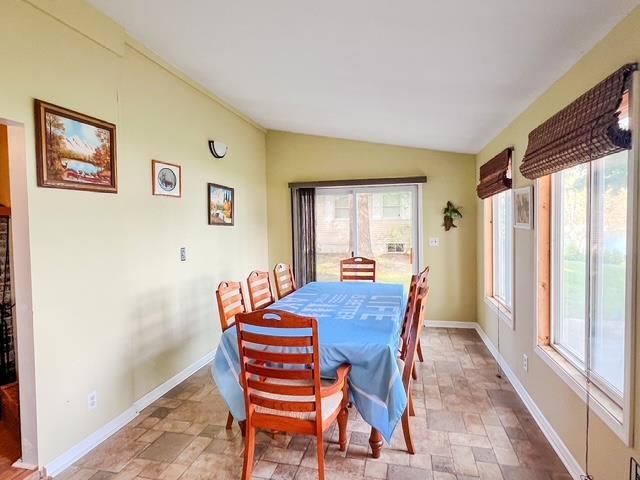 601 N Scott Dr, Farwell, MI 48622 - dining area with stone tile floors, vaulted ceiling, and healthy amount of natural light