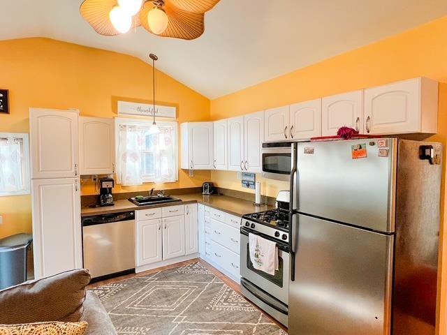 601 N Scott Dr, Farwell, MI 48622 - kitchen featuring appliances with stainless steel finishes, vaulted ceiling, a sink, white cabinets, and hanging light fixtures