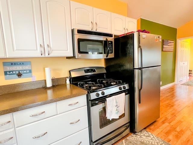 601 N Scott Dr, Farwell, MI 48622 - kitchen with appliances with stainless steel finishes, light wood-type flooring, white cabinetry, and dark countertops