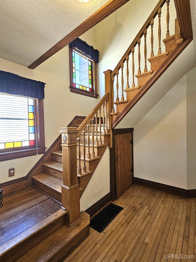 120 N Pewabic St, Laurium, MI 49913 - staircase featuring plenty of natural light, hardwood / wood-style flooring, a textured ceiling, and baseboards