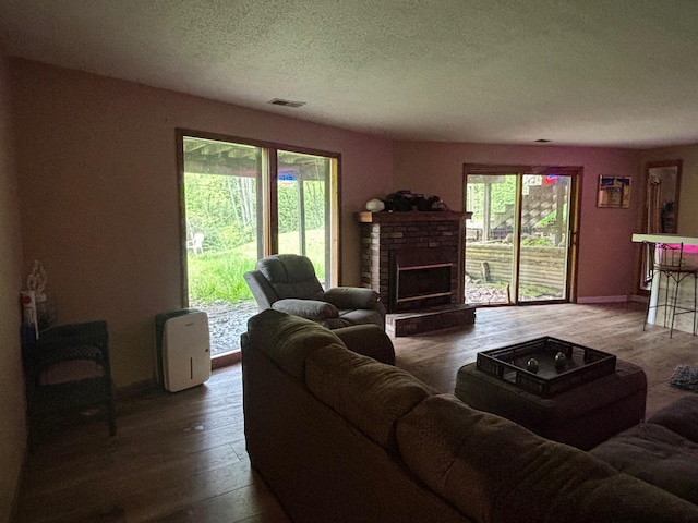 2913 W Howard Rd, Beaverton, MI 48612 - living area featuring hardwood / wood-style flooring, a brick fireplace, a textured ceiling, and baseboards