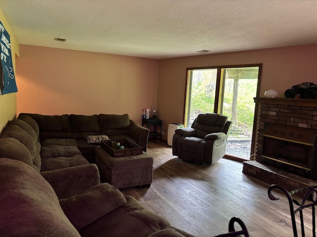 2913 W Howard Rd, Beaverton, MI 48612 - living area featuring hardwood / wood-style flooring, a textured ceiling, and a brick fireplace