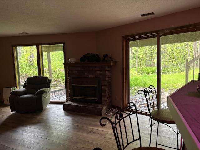 2913 W Howard Rd, Beaverton, MI 48612 - living area with a textured ceiling, wood-type flooring, plenty of natural light, and a brick fireplace