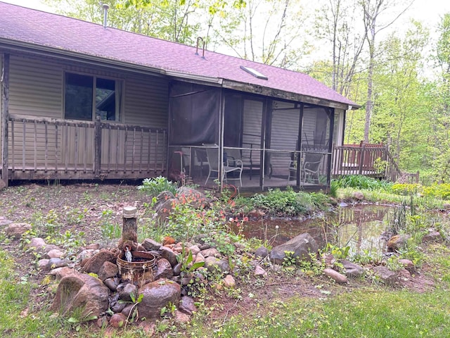 2913 W Howard Rd, Beaverton, MI 48612 - back of property featuring a sunroom, a shingled roof, and a wooden deck