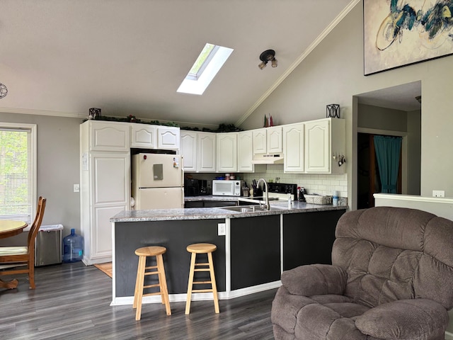 2913 W Howard Rd, Beaverton, MI 48612 - kitchen with white appliances, a skylight, under cabinet range hood, open floor plan, and a peninsula
