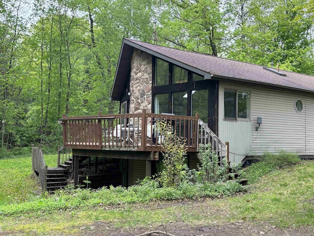 2913 W Howard Rd, Beaverton, MI 48612 - view of front facade featuring stairway, a wooden deck, roof with shingles, and stone siding
