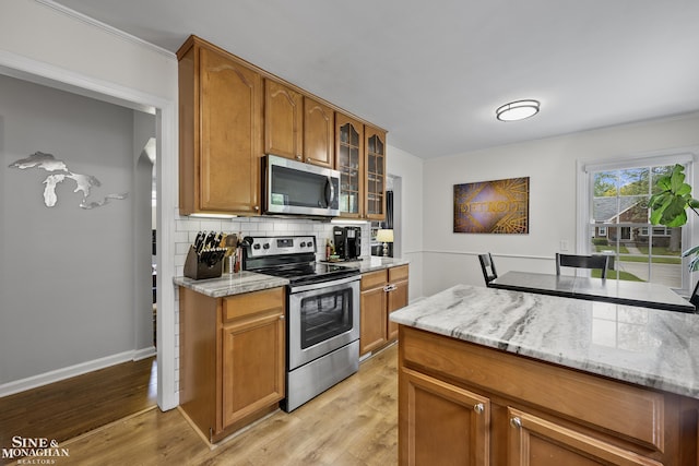 1873 Manchester Blvd, Grosse Pointe Woods, MI 48236 - kitchen with stainless steel appliances, tasteful backsplash, light wood-style floors, glass insert cabinets, and brown cabinetry